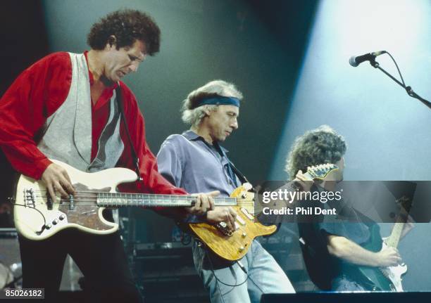 Photo of Phil PALMER and John ILLSLEY and DIRE STRAITS and Mark KNOPFLER; L-R: John Illsley, Mark Knopfler, Phil Palmer - performing live onstage