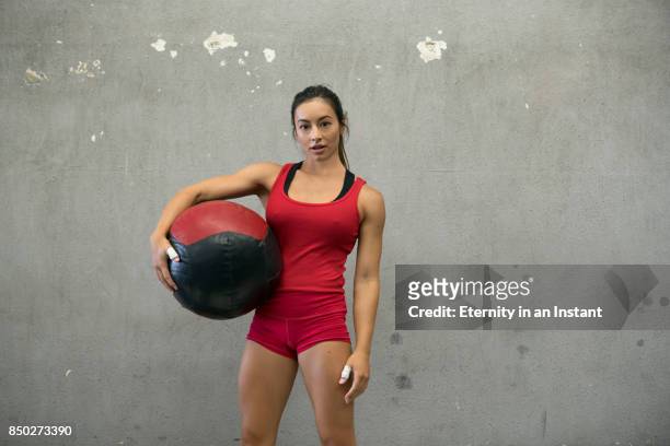 young woman holding a medicine ball in a gym - entrenamiento combinado fotografías e imágenes de stock