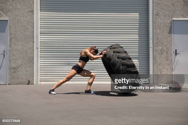young woman lifting a giant tire - 舉重訓練 個照片及圖片檔