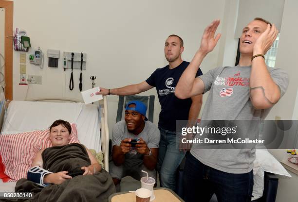 New England Revolution Cody Cropper and Brad Knighton watch as teammate Claude Dielna plays video games with Tobin at Boston Children's Hospital...