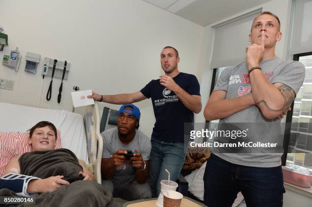 New England Revolution Cody Cropper and Brad Knighton watch as teammate Claude Dielna plays video games with Tobin at Boston Children's Hospital...