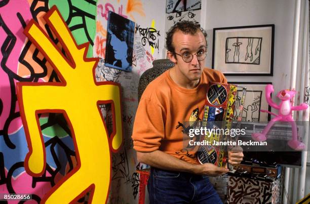 American artist Keith Haring holding a decorated radio cassette player in his studio, New York City, 1985.