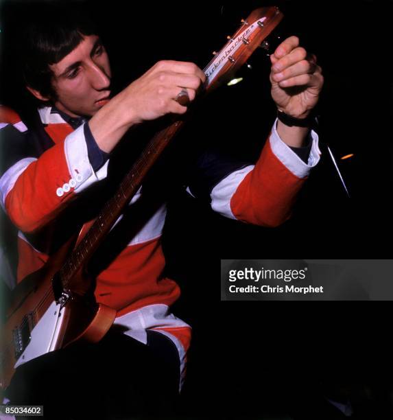 Photo of Pete TOWNSHEND and The Who; Pete Townshend performing live onstage, re-stringing guitar, wearing Union Jack jacket