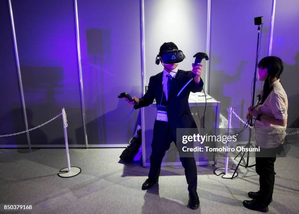 Visitor wearing a an HTC Corp. Vive virtual reality headset plays a video game in the Intel Corp. Booth during the Tokyo Game Show 2017 at Makuhari...