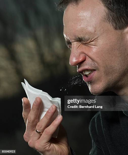 man sneezing into tissue - adult drooling stock-fotos und bilder