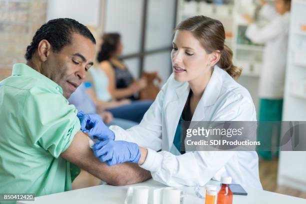 l'operatore sanitario premuroso posiziona la benda sul braccio dell'uomo - shopping male foto e immagini stock