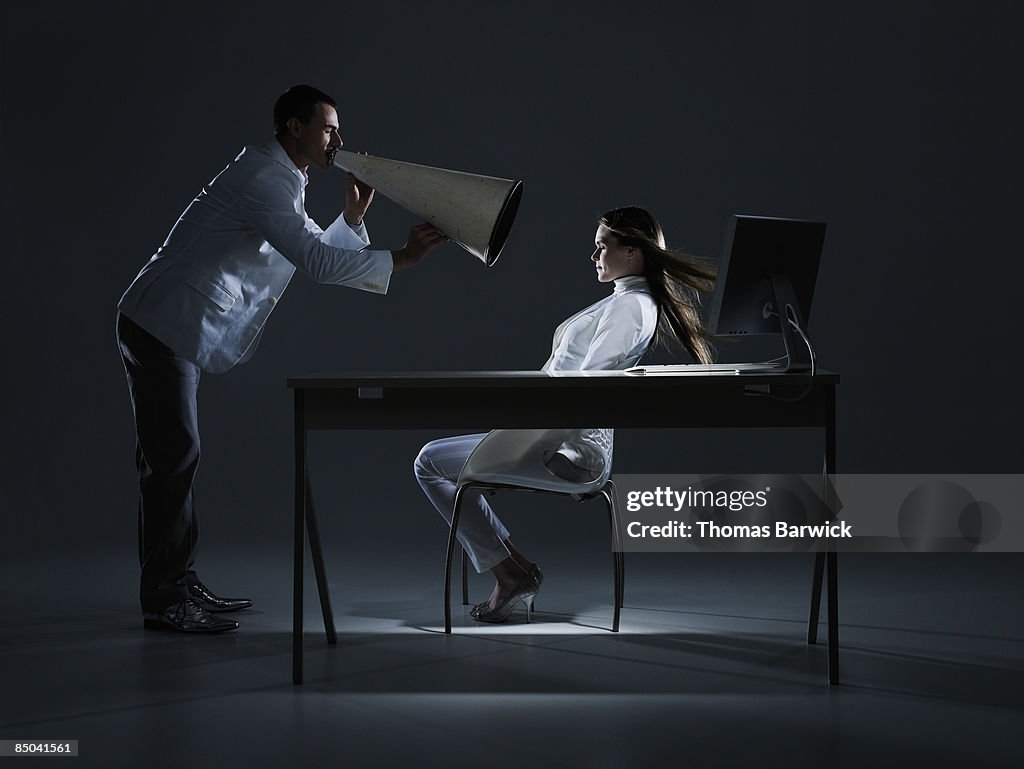 Businessman yelling at woman through megaphone