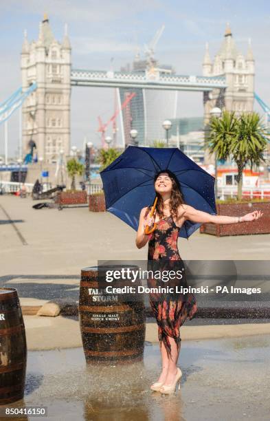 Model Leticia Basgal stands inside an interactive storm installation, which creates wind and rain, at a photocall at Shad Thames, in central London.