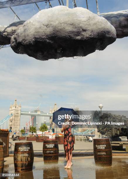 Model Leticia Basgal stands inside an interactive storm installation, which creates wind and rain, at a photocall at Shad Thames, in central London.