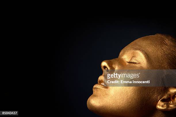 gold young woman  with eyes closed - female body painting stock-fotos und bilder