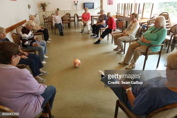 Elderly women kick a soccer ball while they remain seated to one another during an hour-long session of physical exercise at the Mireille Mathieu...