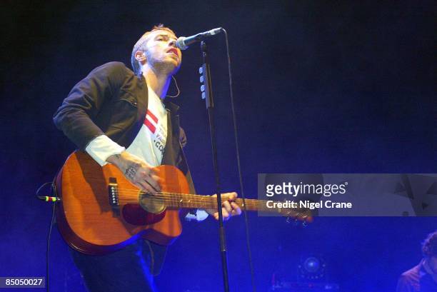 Photo of COLDPLAY and Chris MARTIN; Chris Martin performing live onstage, wearing make trade fair t-shirt, playing Martin acoustic guitar