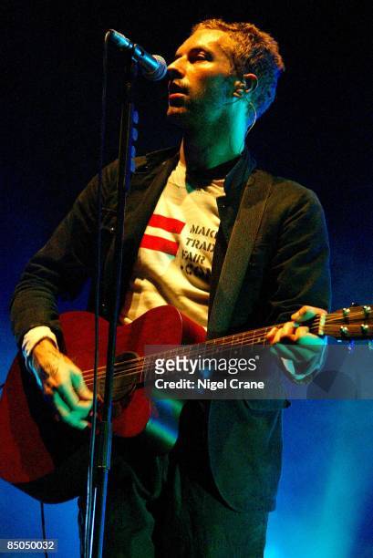 Photo of Chris MARTIN and COLDPLAY; Chris Martin performing live onstage, wearing make trade fair t-shirt, playing Martin acoustic guitar