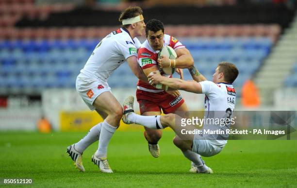 Wigan Warriors Ben Flower is tackled by Salford City Reds' Andrew Dixon and Theo Fages during the Super League match at the DW Stadium, Wigan.