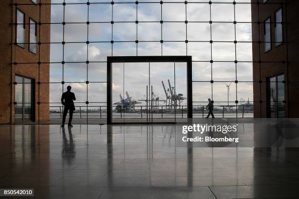 Pedestrians pass the HHLA Container Terminal Tollerort as shipping cranes stand on the dockside beyond at the Port of Hamburg in Hamburg, Germany, on...