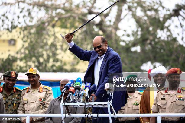 Sudanese President Omar al-Bashir waves a walking stick as he gives a speech in Nyala, the capital of South Darfur province, on September 21 while...