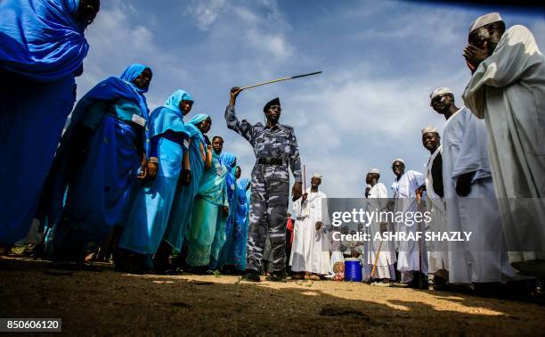 Sudanese soldier waves a baton as he walks in a procession during President Omar al-Bashir's tour in Nyala, the capital of South Darfur province, on...