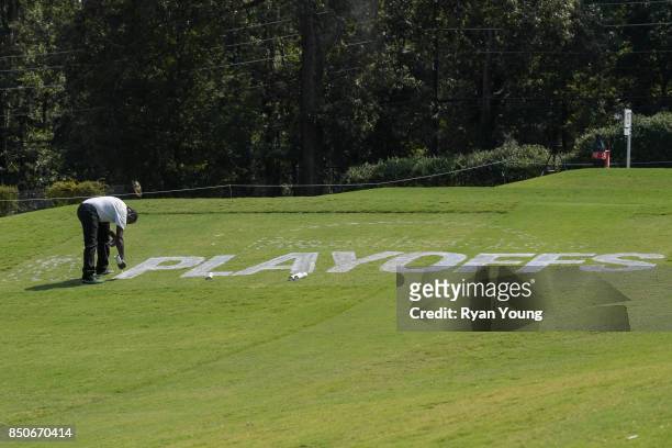Worker spray paints in the FedEx Cup Playoffs logo during practice for the TOUR Championship, the final event of the FedExCup Playoffs, at East Lake...