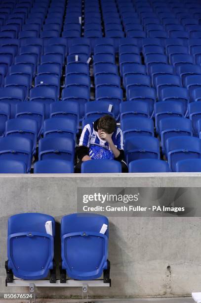 Dejected Brighton & Hove Albion fan sits alone in the stands