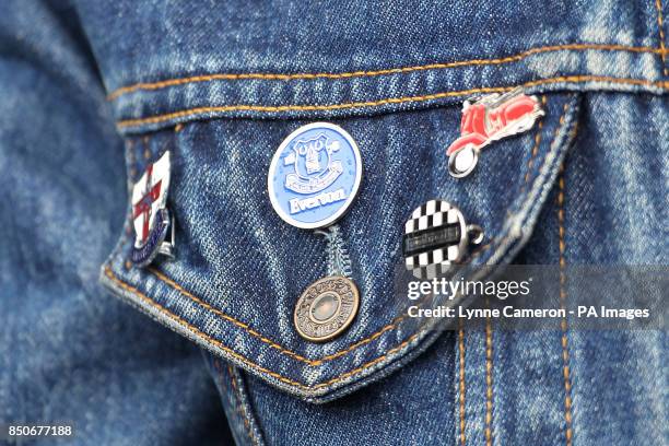 An Everton fan proudly displays their enamel badges on their jacket