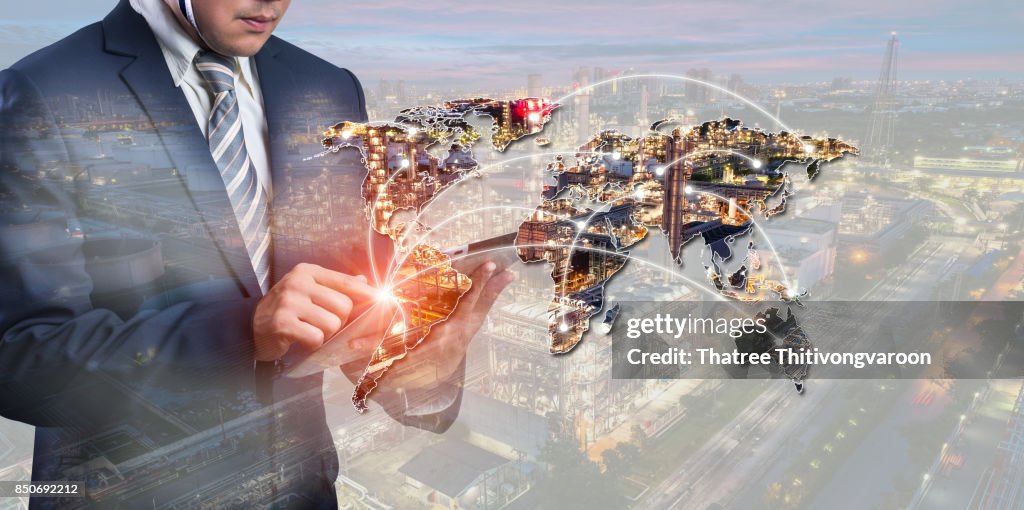 Energy power concept : double exposure of businessmen using smart phone with Oil and gas industry - refinery factory - petrochemical plan on world map background