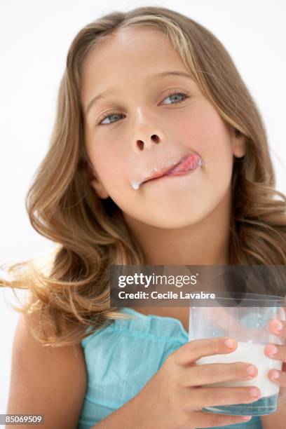 little girl licking milk off upper lip - licking lips stock pictures, royalty-free photos & images