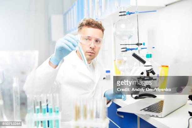 man working in laboratory - mid adult stock-fotos und bilder