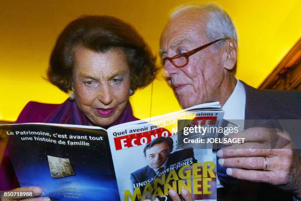 Liliane Bettencourt , fille du fondateur du géant des cosmétiques L'Oréal et son mari André lisent le 20 novembre 2002 à Paris, l'article consacré au...