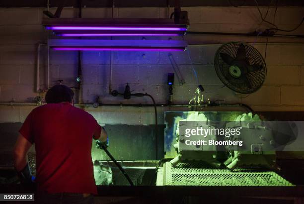 An employee washes off a solution that is used to reveal imperfections under black light from a casting at the Lite Metals Co. Foundry in Ravenna,...
