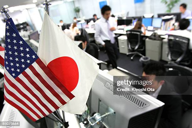 Flags of the USA and Japan are seen while traders work at Gaitame.com, a foreign exchange trading company, on February 25, 2009 in Tokyo, Japan. The...