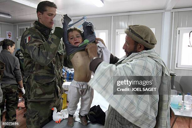 An Aghan child is treated by a French doctor of the 27th BCA on February 19, 2009 at the Morales-Frazier Forward Operating Base in Nijrab, Kapisa...