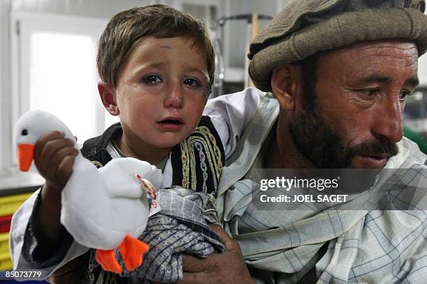 An Afghan man waits with his sick child to be treated by French doctors of the 27th BCA on February 19, 2009 at the Morales-Frazier Forward Operating...