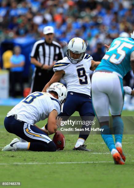 Younghoe Koo kicks a fieldgoal as Drew Kaser of the Los Angeles Chargers holds during the second half of a game against the Miami Dolphins at StubHub...