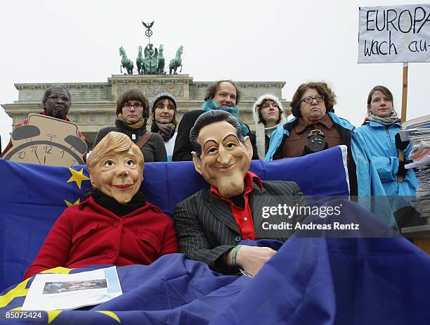 Two members of the Society for Threatened Peoples organisation dressed up as German Chancellor Angela Merkel and French President Nicolas Sarkozy lie...