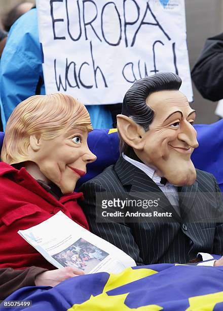 Two members of the Society for Threatened Peoples organisation dressed up as German Chancellor Angela Merkel and French President Nicolas Sarkozy lie...
