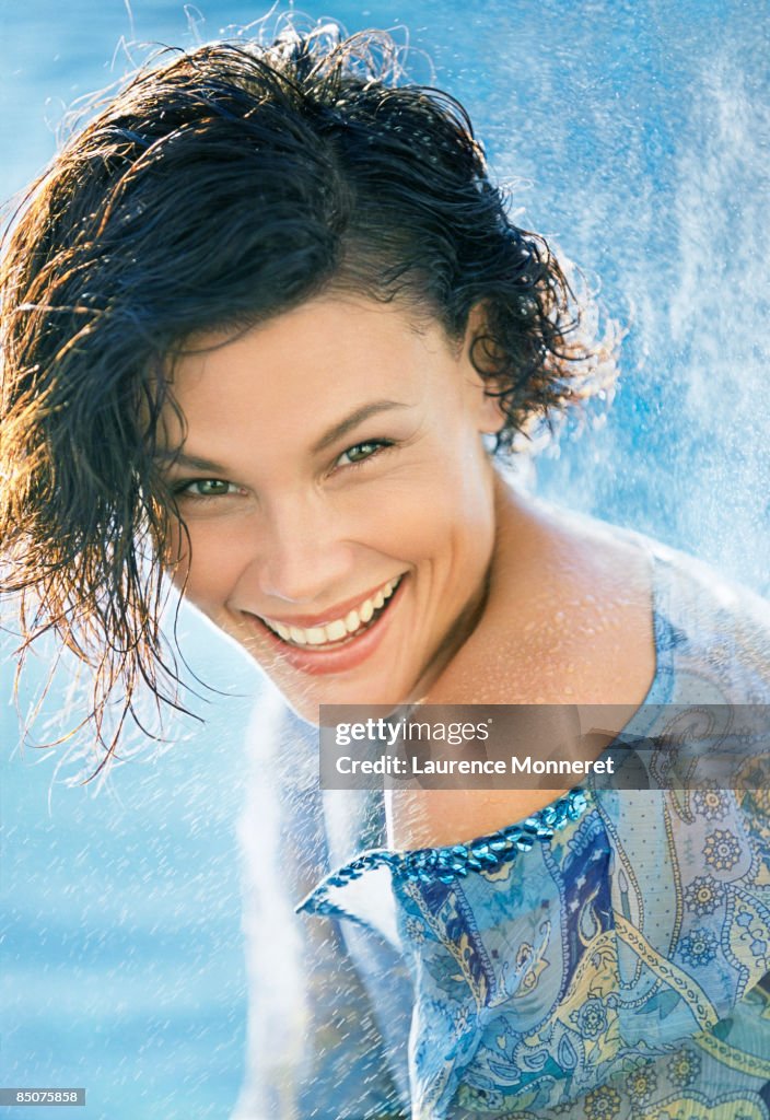 Laughing woman with wet hair sprayed by water