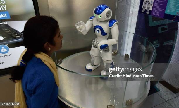 Staff of Canara Bank demonstrates Candi, the robot which welcomes customers as receptionists at Bengaluru Circle Office on September 21, 2017 in...