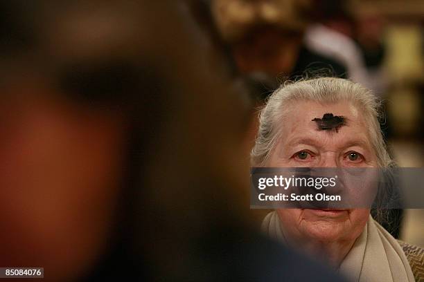 Woman with a cross of ashes on her forehead paticipates in an Ash Wednesday mass in the cafeteria of Holy Name Cathedral February 25, 2009 in...