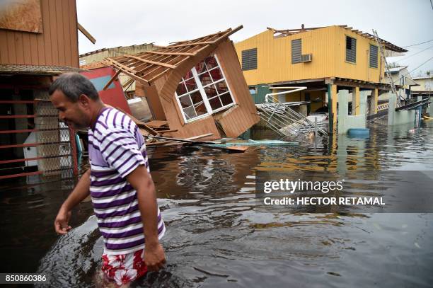 Man walks past a house laying in flood water in Catano town, in Juana Matos, Puerto Rico, on September 21, 2017. Puerto Rico braced for potentially...