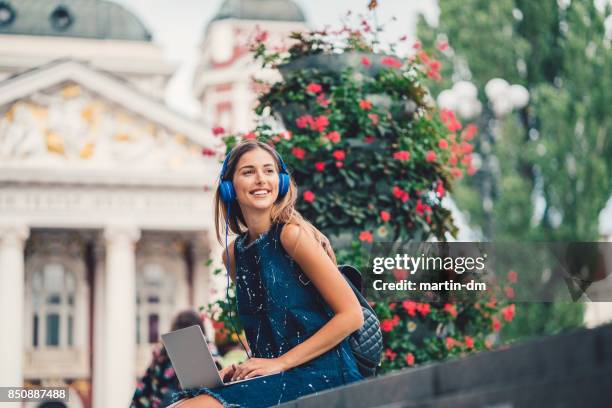 mujer sonriente fuera de uso portátil y escuchar podcasts - musica y verano fotografías e imágenes de stock