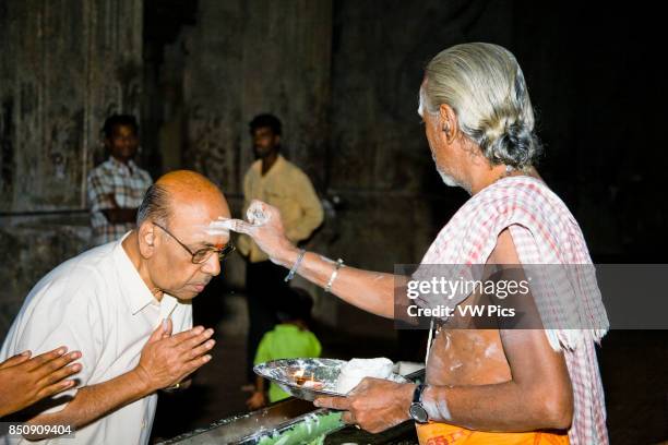 Brahmin applying a tikka to a man?s forehead, Meenakshi Temple, Madurai, Tamil Nadu, India.