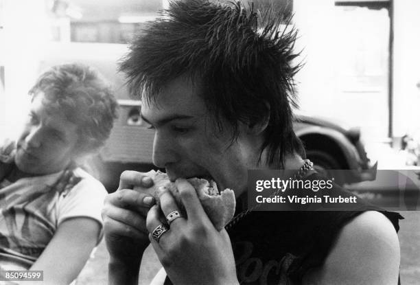 Photo of Steve JONES and Sid VICIOUS and SEX PISTOLS; Sid Vicious eating with Steve Jones on set of the Pretty Vacant video