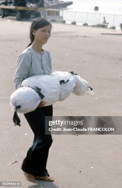 Une jeune femme porte dans ses bras un cadavre recouvert d'un plastique, à Saïgon, Vietnam le 7 avril 1975.