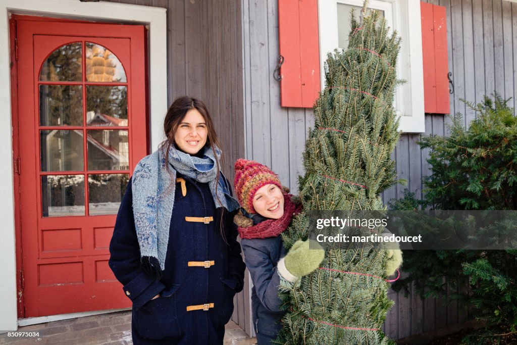 Zwei Schwestern mit schneiden frisch Weihnachtsbaum vor Haus im Freien.