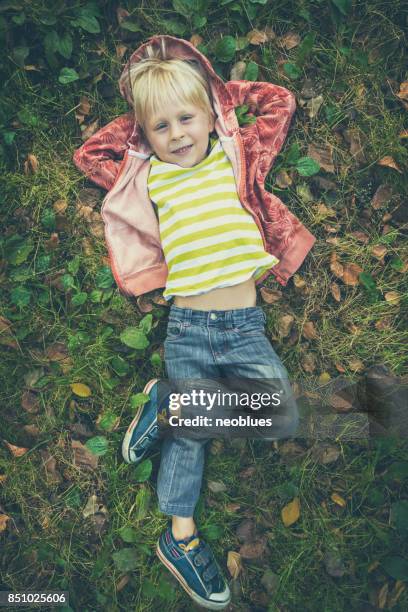 laughing boy laying on the autumn leaves - hands behind head stock pictures, royalty-free photos & images