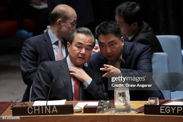 Chinese Foreign Minister Wang Yi speaks with a member of the Chinese delegation during a UN Security Council meeting concerning nuclear...