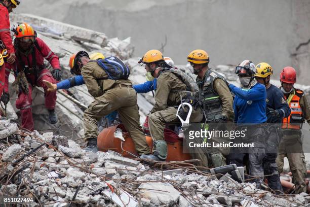 Israeli and Mexican rescuers work at the top of a destroyed building trying to recover the body of a man two days after the magnitude 7.1 earthquake...