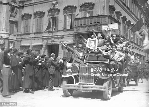 Rome, Italy, June 4, 1944. Catholic Partisans on a car applaud the Pope Pio XII waving the Italian flag with Savoy shield, forgetting that the...