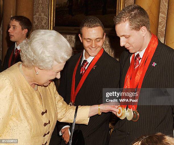 Queen Elizabeth II admires the medals of swimmer Matt Walker during a reception for the Great Britain Paralympic team at Buckingham Palace on...