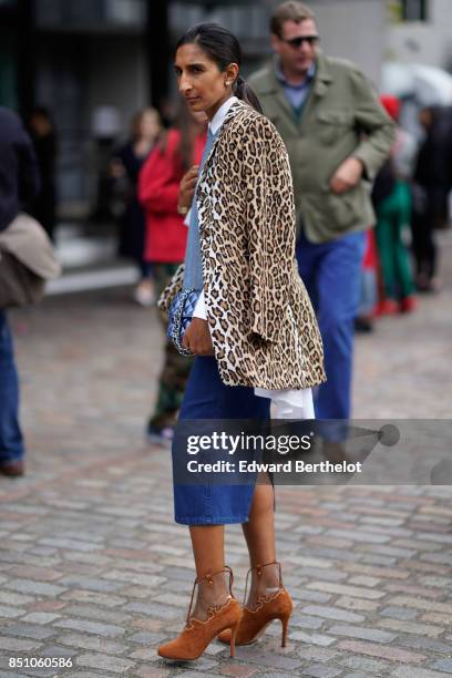 Guest wears a leopard print jacket, a blue denim skirt, brown shoes, outside Preen by Thornton Bregazzi, during London Fashion Week September 2017 on...